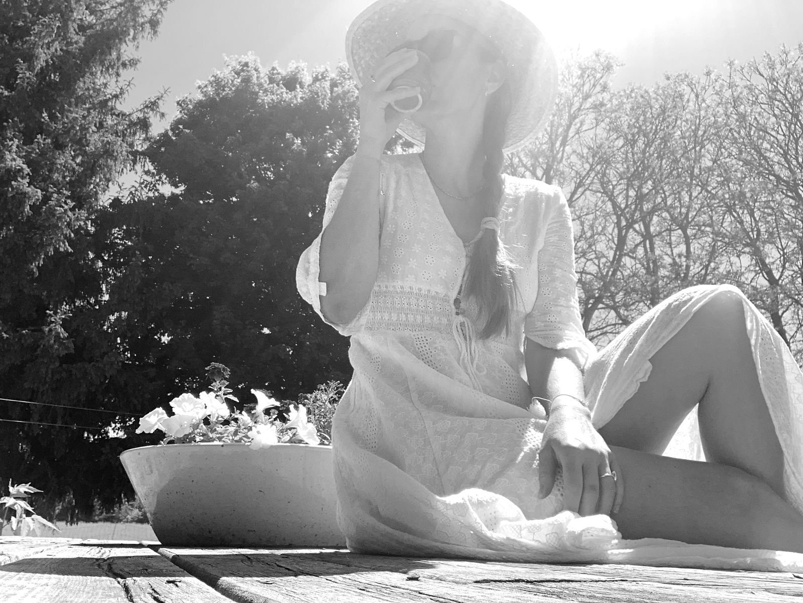 Woman with hat sitting and drinking tea.