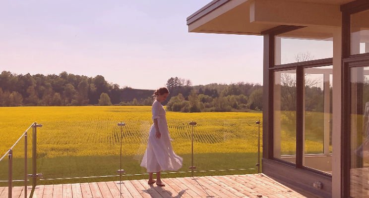 Woman in white dress in front of a field